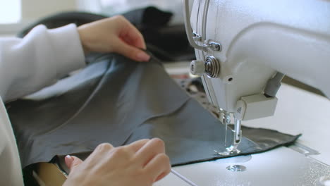 Small-business-and-hobby-concept.-Young-woman-designer-clothes-working-on-a-sewing-machine-in-her-studio.-Indoors